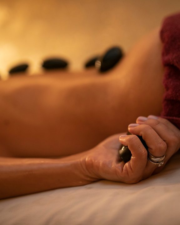 Woman lying during a hot stone massage with warm stones on her back.