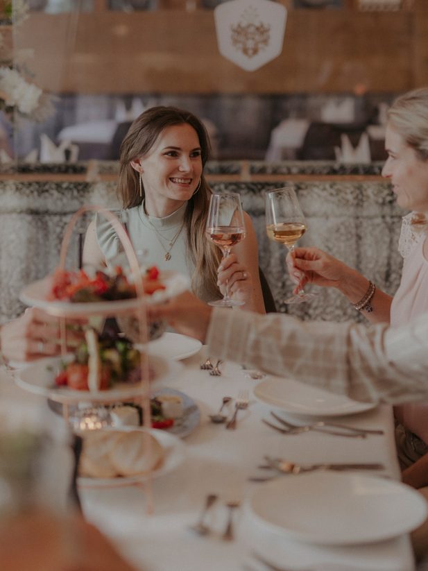 Gäste stoßen im Restaurant am gedeckten Tisch mit Gläsern an.