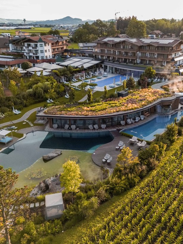Aerial view of a hotel resort with spa area and pool complex next to a vineyard.