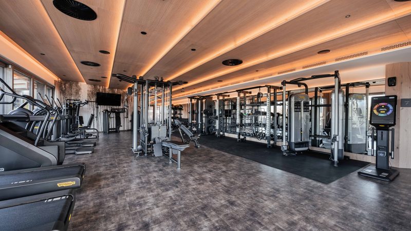 Modern gym with treadmills, strength machines and mirrored wall.