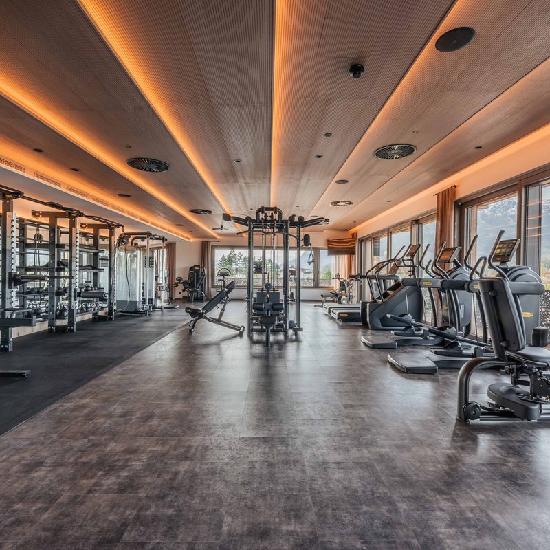 Modern fitness room with strength and cardio equipment in front of large windows with mountain views.