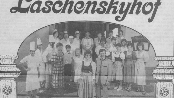 Black-and-white group photo of staff and guests in front of the entrance with the “Laschenskyhof” sign.
