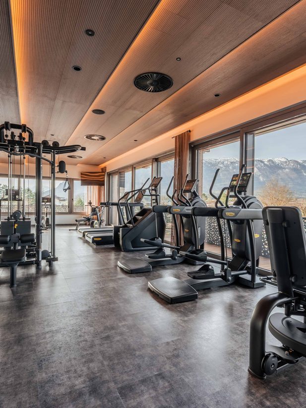 Fitness room with strength and cardio equipment by large windows overlooking the mountains.