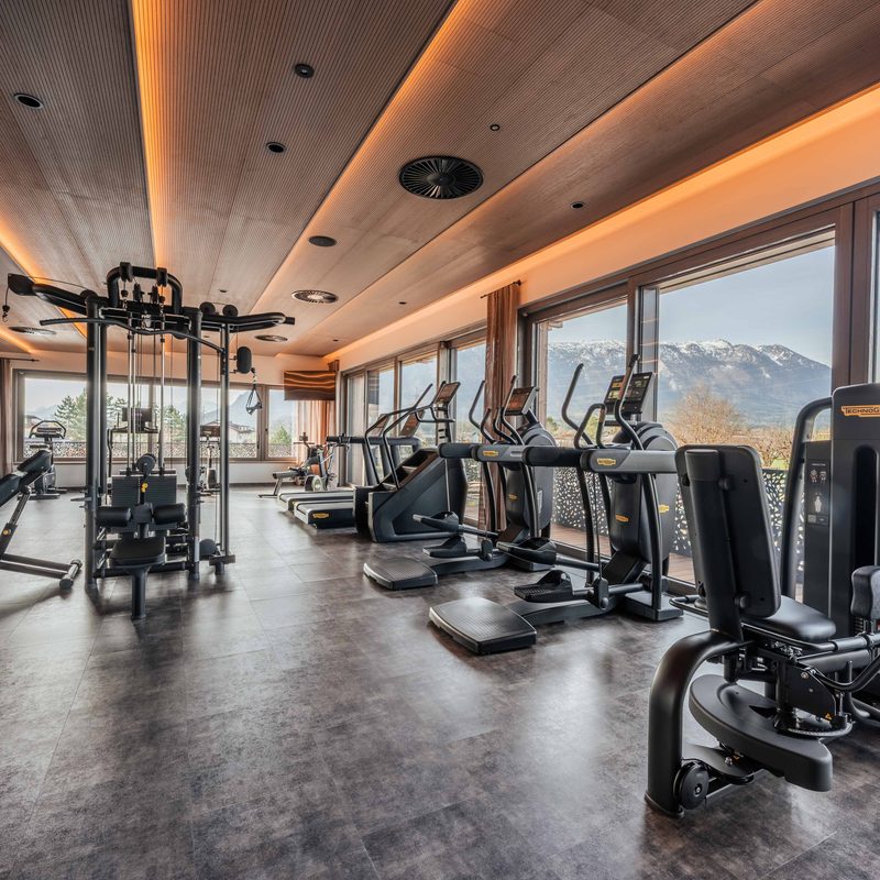 Fitness room with strength and cardio equipment by large windows overlooking the mountains.