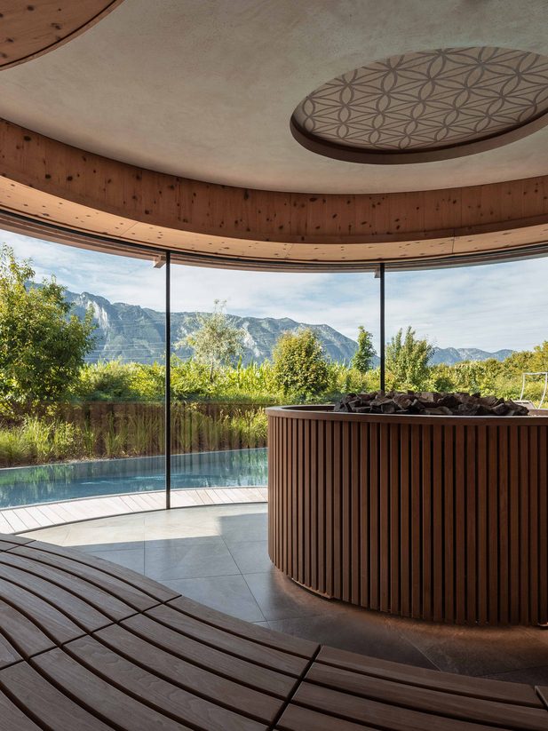 Spa relaxation room with wood interior, panoramic windows, and views of pool and mountains.