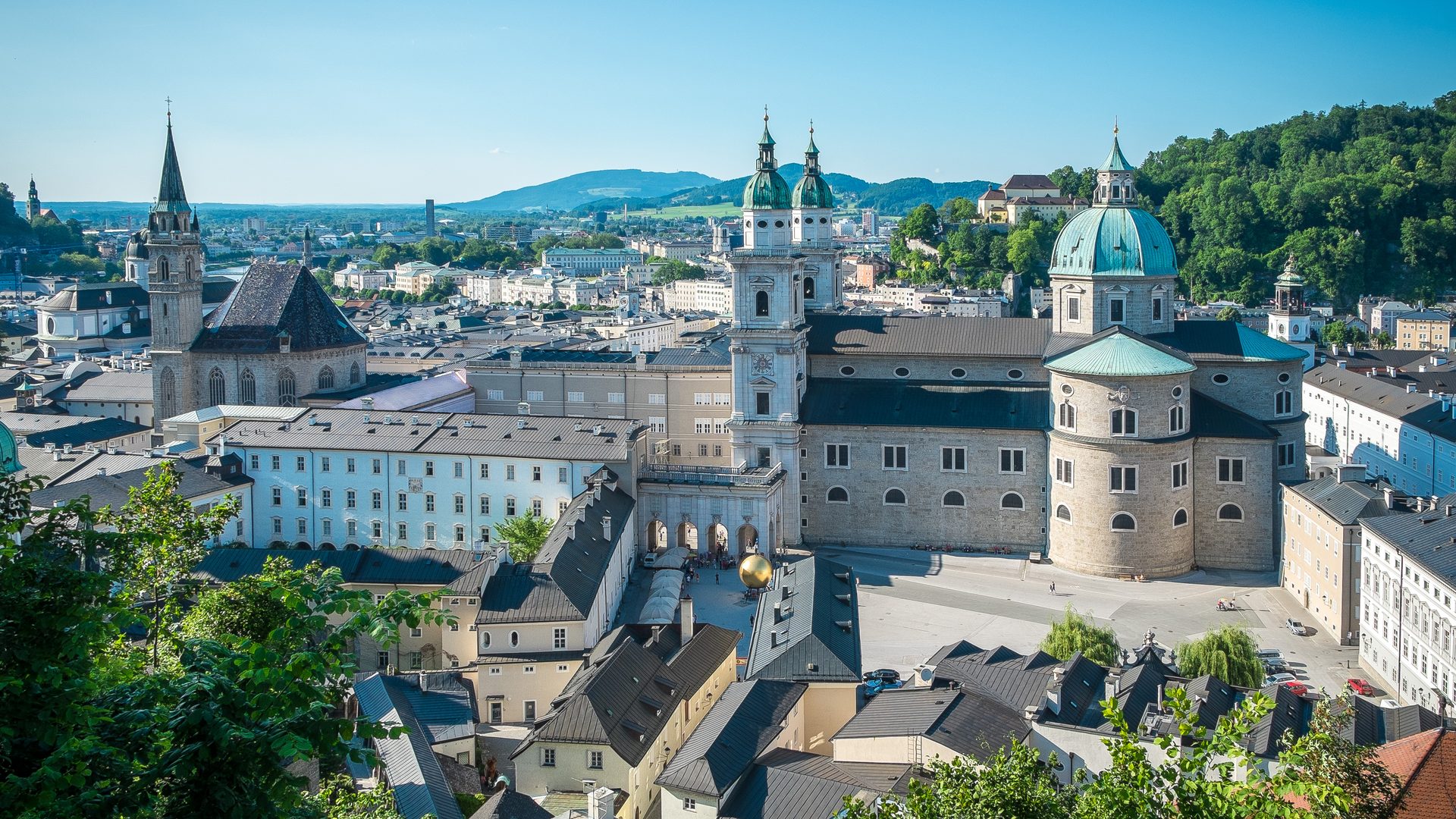 Panoramic view of the old town with a cathedral dome, church towers and many rooftops in the foreground.